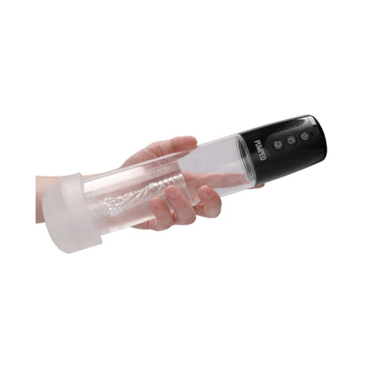 A hand holding a transparent cylindrical device with a black top featuring three buttons and a soft white base, resembling the Shots Pumped Automatic Cyber Pump Masturbation Sleeve with Silicone Cock Ring.