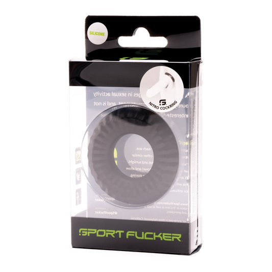 A black silicone cock ring from Sport Fucker is presented in a transparent plastic box featuring white and green text and logos. The rectangular packaging showcases the Sport Fucker Nitro Ring label, combining a sleek design with sporty appeal.