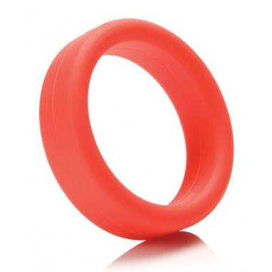 A bright red Tantus 1.5 Supersoft C Ring stands on a reflective surface, creating a subtle reflection. Its smooth silicone design contrasts against the white background, highlighting its striking hue.