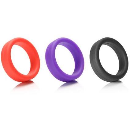 Three Tantus 1.5 Supersoft C Rings in red, purple, and black are displayed side by side on a reflective white surface, highlighting their vibrant allure and promise of comfort.