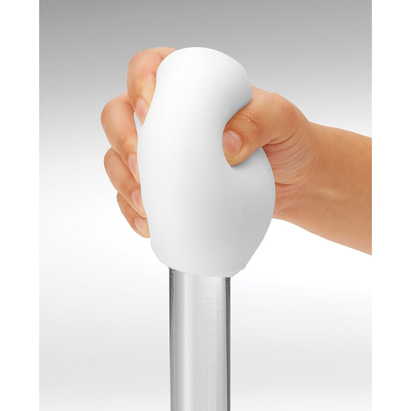 A hand grips the reusable white rounded handle of a Tenga GEO Glacier by Tenga, attached to a metal pole against a gray background.