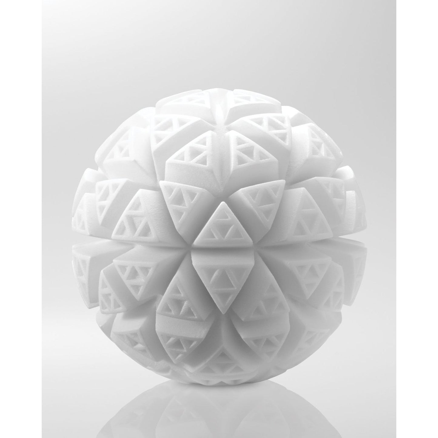 A 3D rendering of a white textured sphere with intricate geometric patterns reminiscent of the Tenga GEO Glacier - White by Tenga, featuring triangles and diamond shapes like folded layers. Made from stretchable, reusable material, it stands against a gradient from light gray to white.