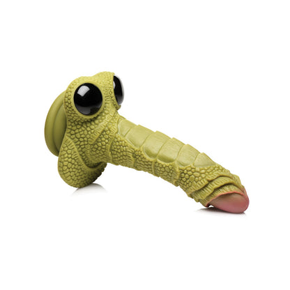 The Creature Cocks Swamp Monster Scaly Silicone Dildo in yellow-green is a playful silicone toy, featuring a cartoonish dinosaur head with large black eyes, a pebbled texture, and an elongated snout ending in a pink tongue. It’s positioned at an angle against the white background.