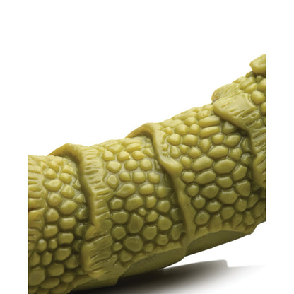 A close-up of the Creature Cocks Swamp Monster Scaly Silicone Dildo - Green shows its textured, phthalate-free silicone with scale-like patterns. Its curved, segmented design contrasts against a plain white background.