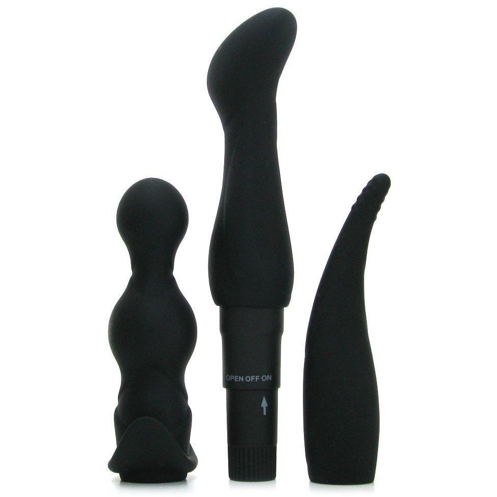 Three black silicone toys from the Pipedream Anal Fantasy Collection Anal Adventure Kit are displayed vertically against a white background. They vary in shape and size, with two bulbous-ended and one pointed with a curved tip. A battery compartment and control dial are seen on one toy.