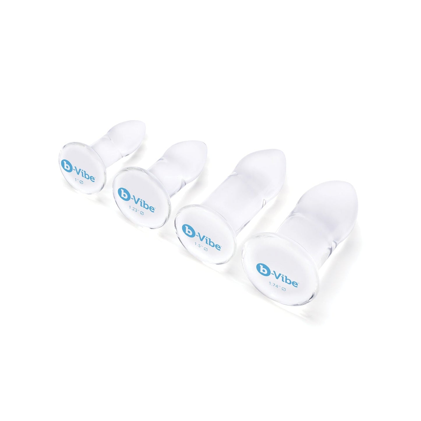 The b-Vibe Glass Anal Dilator 4 pc Set features four transparent, graduated silicone plugs with round bases labeled b-Vibe, arranged by size on a white background and designed for temperature play. Made from hypoallergenic, body-safe materials, they offer safe and pleasurable versatile sizing.