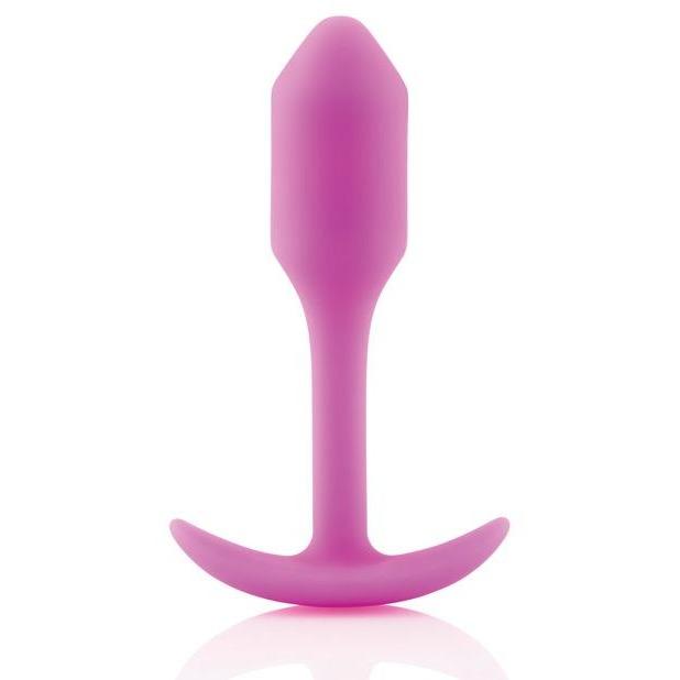 The B-Vibe Snug Butt Plug 1 by b-vibe, made from body-safe pink silicone, features a smooth tapered shape and a T-shaped base, displayed on a white background.