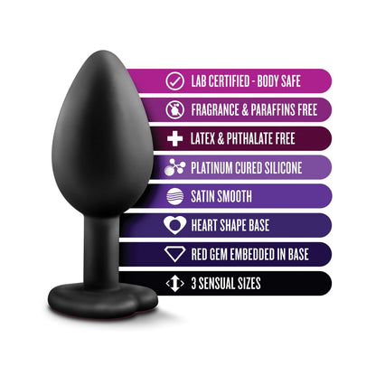 An image of the Blush Luxe Bling Plug by Swiss Navy: a body-safe, black silicone butt plug with a red faux gemstone heart base. It enhances anal training, is lab certified, fragrance and paraffin free, latex and phthalate free, platinum cured, and available in three sizes.