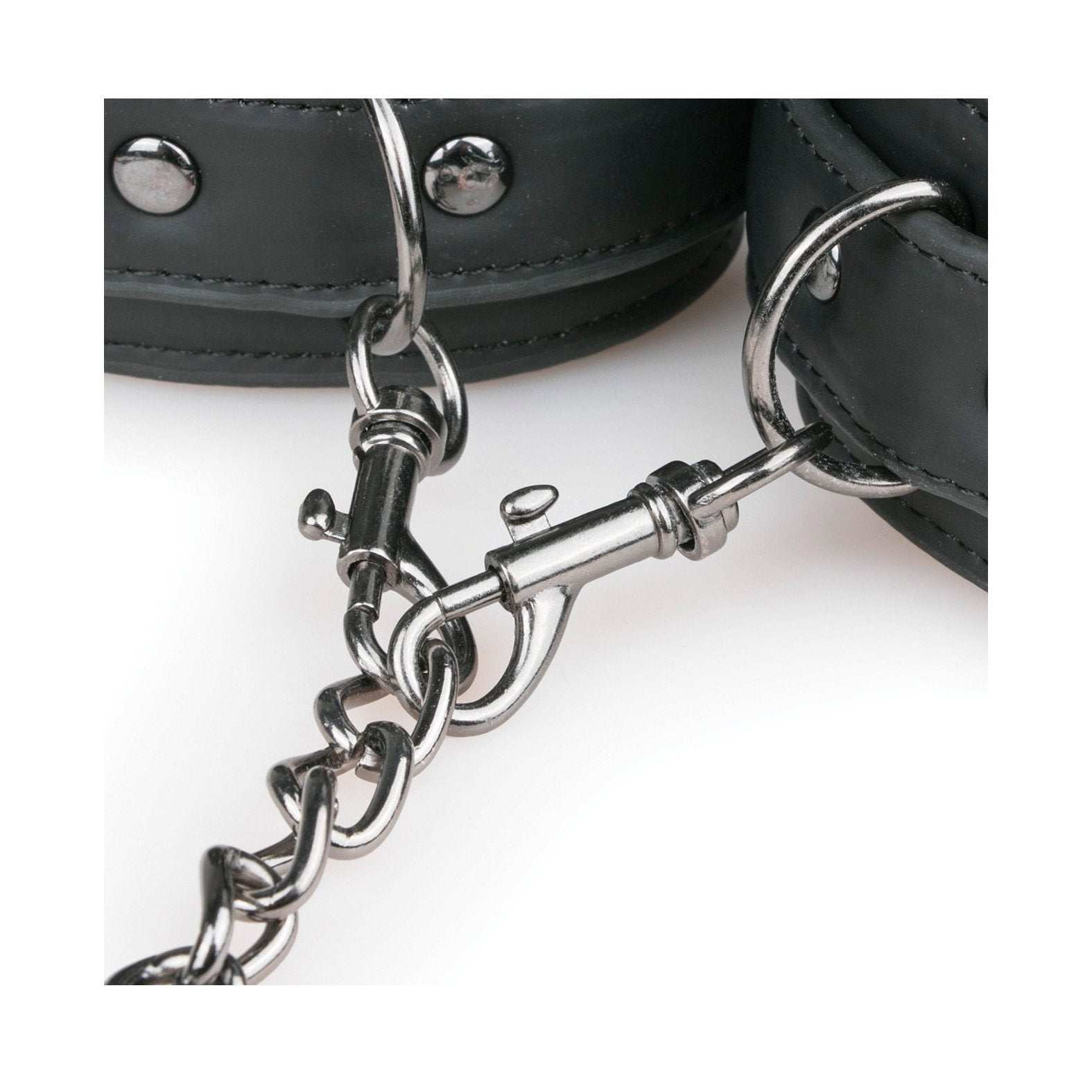 A close-up of Easy Toys Faux Leather Collar with Handcuffs by Easy Toys showcases BDSM handcuffs linked by a metal chain and snap hook, featuring silver studs and metal rings for secure fastening. The image emphasizes the craftsmanship and high-quality materials of these restraints.