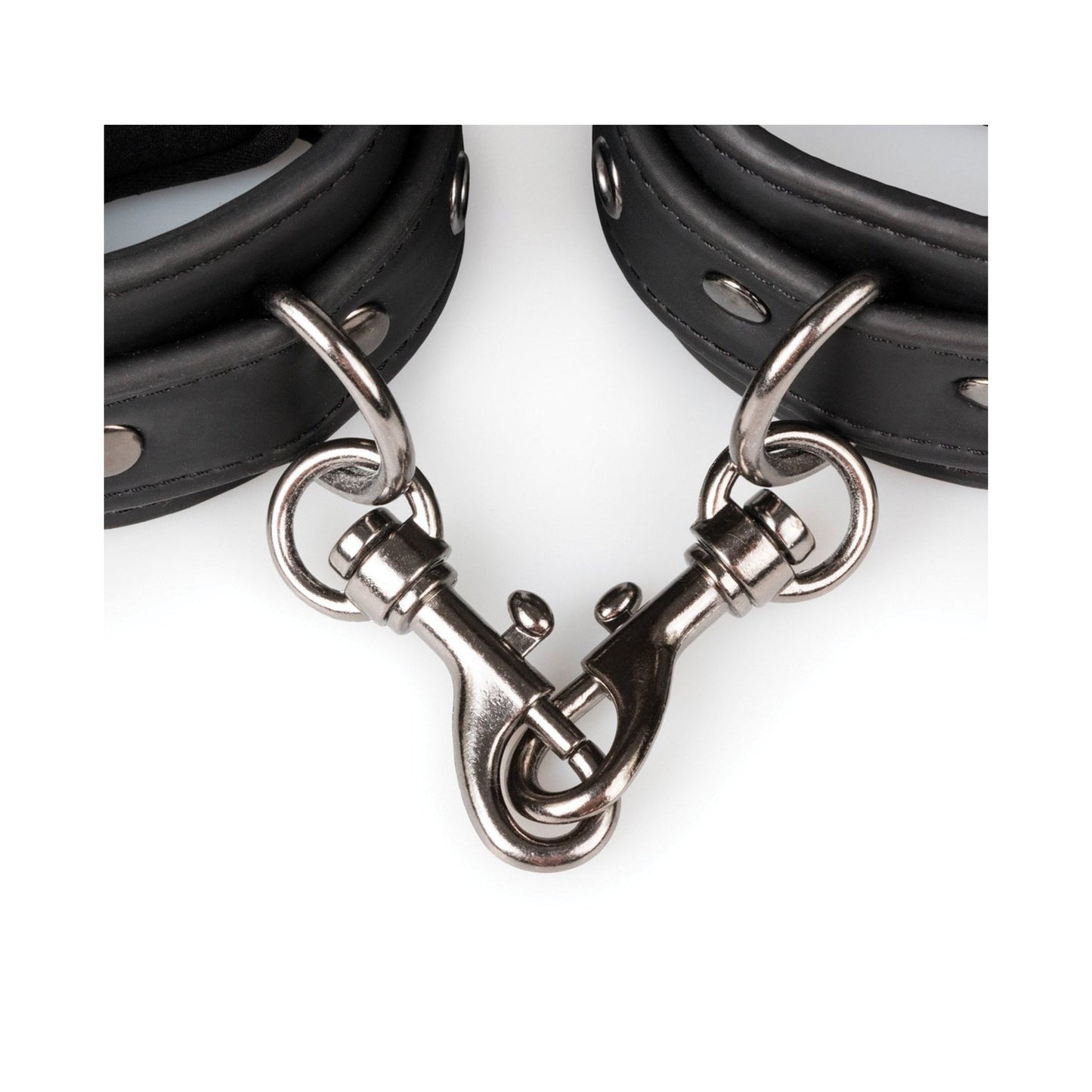 A close-up of Easy Toys Faux Leather Handcuffs reveals two interconnected black leather cuffs. These adjustable restraints from Easy Toys come with metal studs, a swivel clasp, and D-rings for secure attachment.