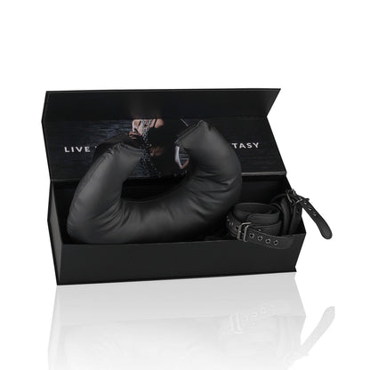 A black Easy Toys bondage kit by Adams Toy Box, with fully adjustable restraints and a padded faux leather item, comes in an open box. The lid shows part of a photo of someone in a chain collar and reads: LIVE YOUR FANTASY.