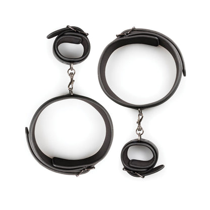 The Easy Toys Thigh & Wrist Cuff Set, a black faux leather restraint set by Easy Toys, features adjustable bondage gear with metal buckles and chains. Displayed on a pristine white background, it includes both thigh and wrist cuffs.