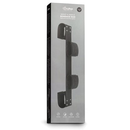 The Easy Toys Wrist & Ankle Bondage Bar comes in a sleek black box, showcasing its faux leather cuffs for restraint. The elegant packaging includes images and white text, adding sophistication to your BDSM collection.