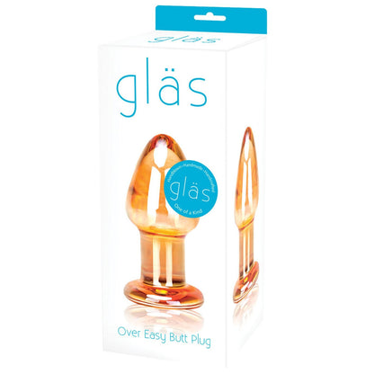 The Gläs Over Easy Butt Plug features stunning packaging that highlights its orange-tinted, hand-blown glass design with a ring handle. Ideal for temperature play, this elegant piece stands out in any display.