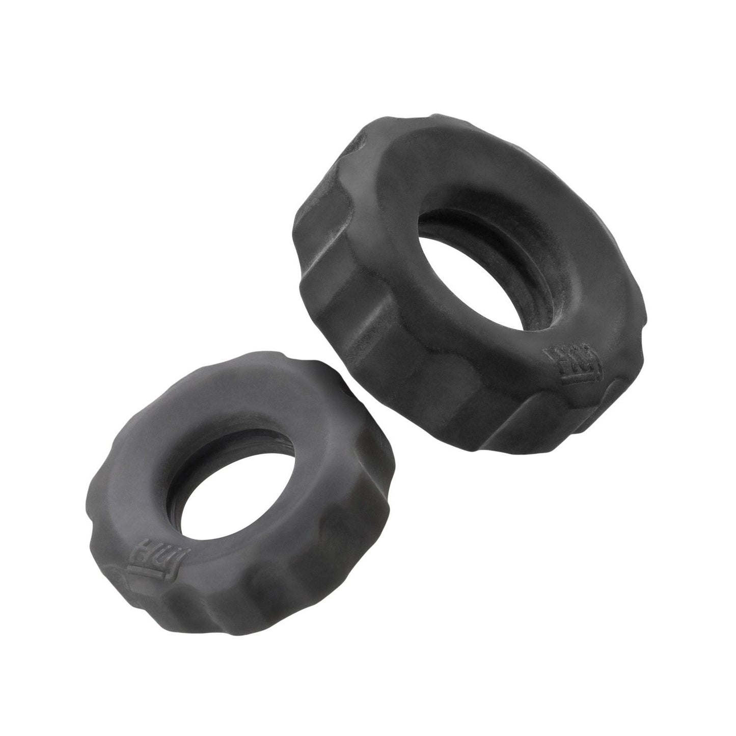 On a white background, two sleek Hunky Junk Cog Rings from the Cog Ring 2 Size Double Pack lie side by side, with the larger ring positioned to the upper right and the smaller to the lower left, both featuring black rubber foam grips.