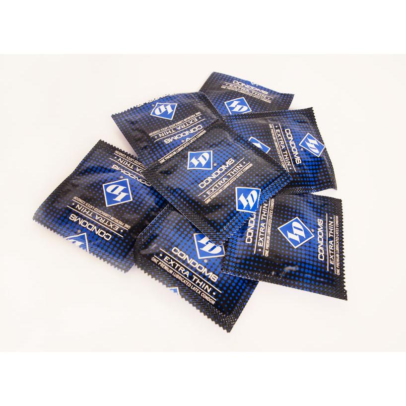 A pile of ID Extra Thin Condoms - Box of 3, in blue and black rectangular packaging, is scattered on a light background. These high-quality lubed condoms are designed to enhance your experience with their ultra-thin material.