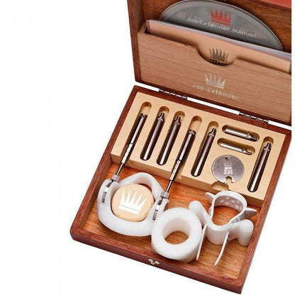A wooden box displaying the Jes Extender Original Standard Penis Enlarger Kit by Jes, containing metallic rods, components, two circular silicone pieces, and an instruction manual. The open box showcases all parts neatly arranged inside.