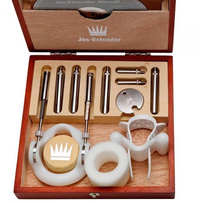 The Jes Extender Original Standard Penis Enlarger Kit by Jes comes in a wooden box and includes metal rods, a plastic support ring, and a silicone band. Each component is organized in compartments alongside the instruction manual for easy use.
