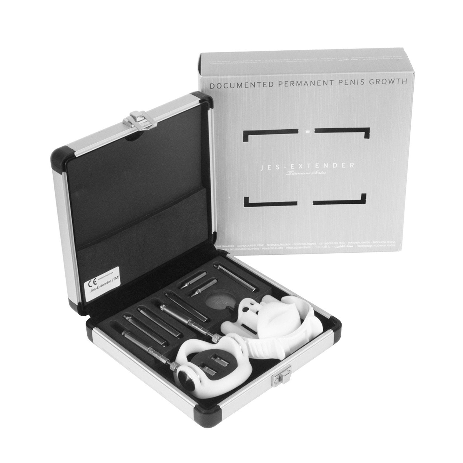 The Jes Extender Titanium Penis Enlarger Kit by Jes comes in a metal case and includes adjustable rods, a base ring, and comfort straps. The packaging in the background claims Documented Permanent Penis Growth as part of this non-surgical method for penis enlargement.