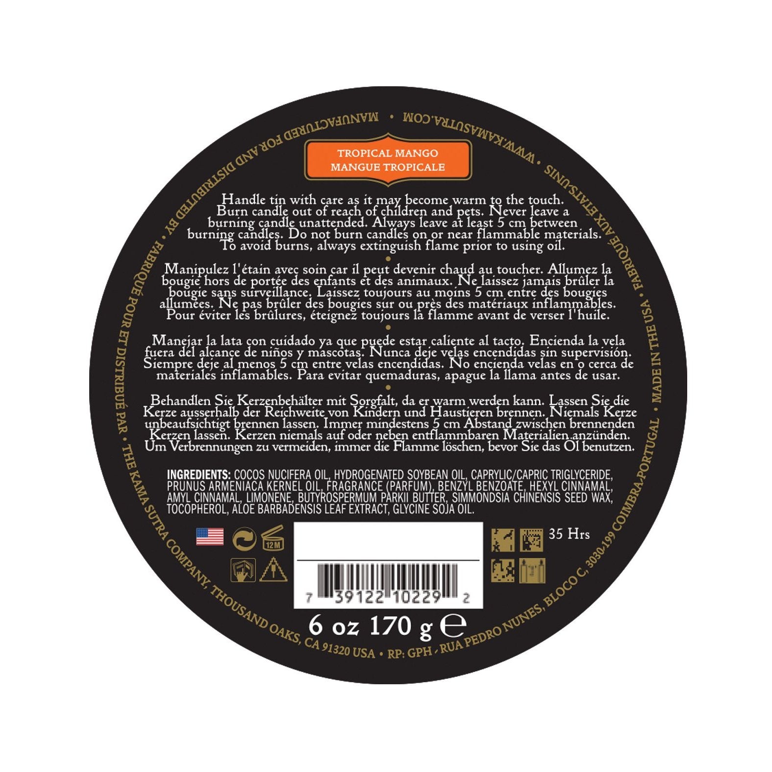 A black circular lid on the Kama Sutra Ignite Massage Candle in Coconut Pineapple shows multilingual safety info, product details, weight (6 oz/170g), 35-hour burn time, and moisturizing formula. It also displays a barcode, manufacturer details, and scent of tropical mango.