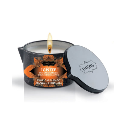 A lit massage candle in a black tin featuring orange and black decor with Karma Sutra Ignite Massage Candle - Coconut Pineapple on the label, offering a deeply sensual experience. The tin lid rests beside it, creating an inviting atmosphere.