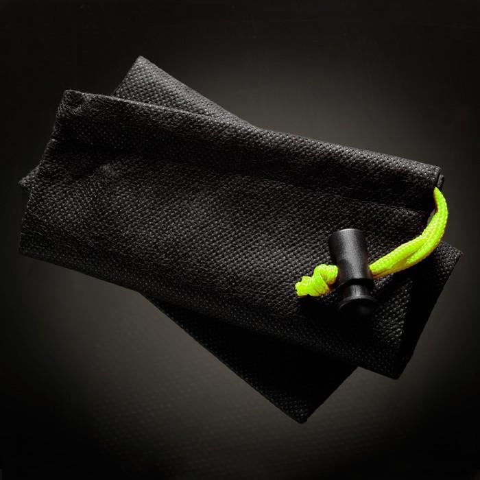 A folded black pouch with a textured surface from the Male Edge Extra Penis Enlarger Kit rests on a dark surface, featuring a neon yellow drawstring with a black lock. The lighting emphasizes its texture and drawstring detail.