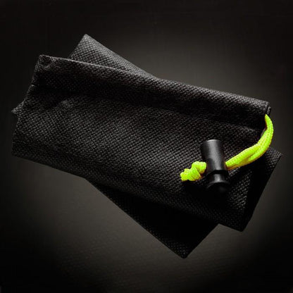A folded black pouch with a textured surface from the Male Edge Extra Penis Enlarger Kit rests on a dark surface, featuring a neon yellow drawstring with a black lock. The lighting emphasizes its texture and drawstring detail.