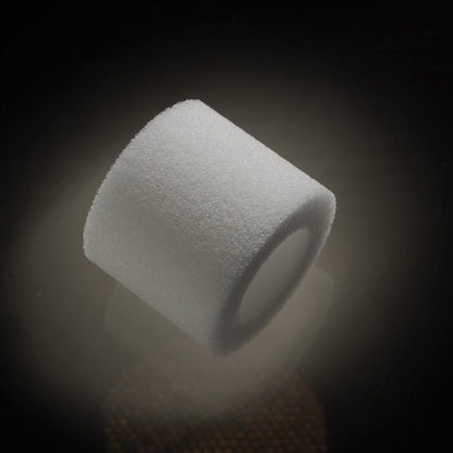 A close-up of a cylindrical, white foam piece from the Male Edge Extra Penis Enlarger Kit against a dark background. The piece appears smooth with a slightly hollow center and is softly illuminated to emphasize its texture.