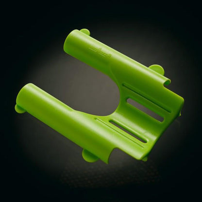 A U-shaped green plastic device with cylindrical sections and slots, reminiscent of the Male Edge Extra Penis Enlarger Kit by Male Edge, is set against a dark background.