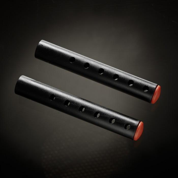 Two black cylindrical objects, similar to the Male Edge Pro Penis Enlarger Kit by Male Edge, featuring holes along their lengths and red caps at one end, set against a dark background.