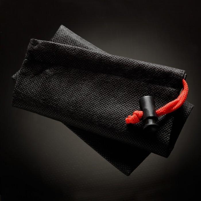 A close-up of a folded black textured pouch from the Male Edge Pro Penis Enlarger Kit features a red drawstring and black toggle, set diagonally on a dark background, with its material alluding to the kits traction technology.