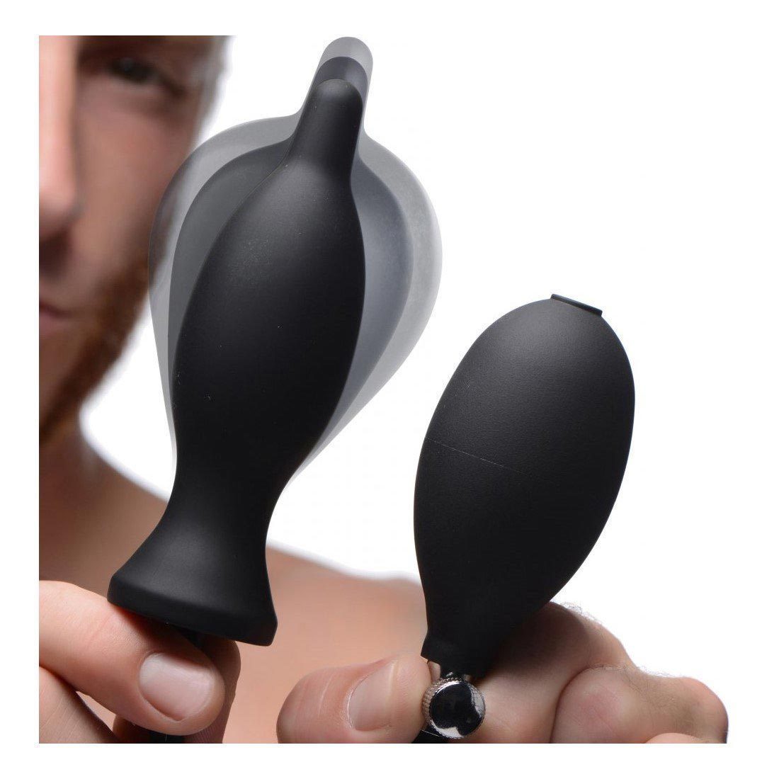 A person holds the Master Series Dark Inflator, a sleek inflatable silicone anal plug with a pump designed for adult use. The black device offers stretching pleasure with its smooth texture, set against a softly blurred background to highlight the product.