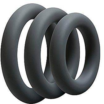 The OptiMale C Ring Kit Thick by Adams Toy Box features three black silicone rings stacked vertically on a white background. Made from super stretchy silicone, they offer comfort and durability for long-lasting erections.