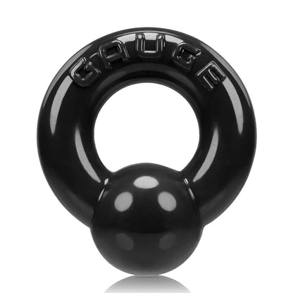 The Oxballs Gauge Cockring is a shiny, black object shaped like a stylized kettlebell with a smaller sphere at the bottom, resembling sleek penis piercing jewelry. GAUGE is embossed on top.