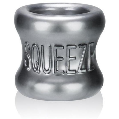 The Oxballs Squeeze Ball Stretcher by Oxballs is a shiny, metallic cylinder with a concave middle, featuring embossed SQUEEZE letters. It is ergonomically designed to reflect light.