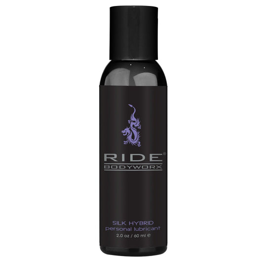 A 2.0 oz / 60 ml black bottle of Ride BodyWorx Silk Hybrid Lubricant from Adams Toy Box features a stylized dragon graphic and white and purple text, promising a long-lasting, body-safe hybrid lube experience.
