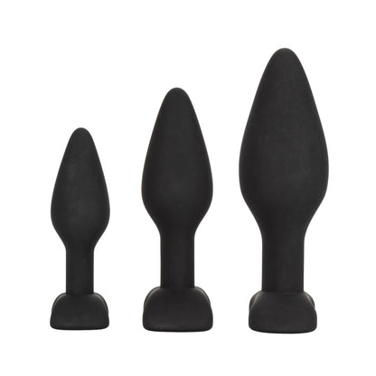 The Silicone Anal Exerciser Kit by California Exotic Novelties includes three black, phthalate-free silicone exercisers with flanged bases for safety, arranged smallest to largest on a white background.