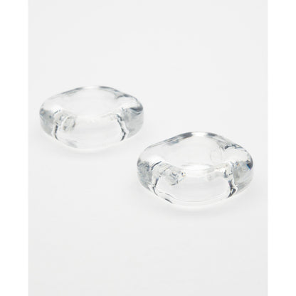 Two clear, rounded glass or acrylic objects are on a white surface. Their smooth curves and slightly concave centers resemble the sleek design of the Sport Fucker Boner Expansion Kit, with their transparent material subtly reflecting light to exude understated elegance.