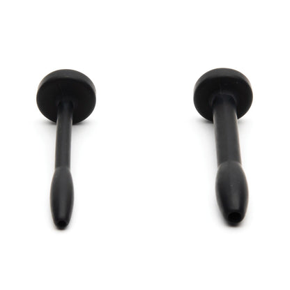 Against a white background, two black elongated rubber objects with flat ends resemble suction cups or plugs and feature rounded handles and tapered bases. They are made from medical-grade silicone, similar to the Sport Fucker Cum Plug Kit by Sport Fucker.