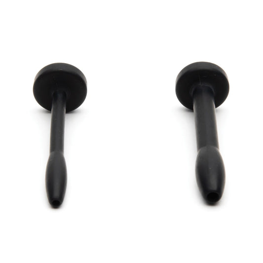 Against a white background, two black elongated rubber objects with flat ends resemble suction cups or plugs and feature rounded handles and tapered bases. They are made from medical-grade silicone, similar to the Sport Fucker Cum Plug Kit by Sport Fucker.