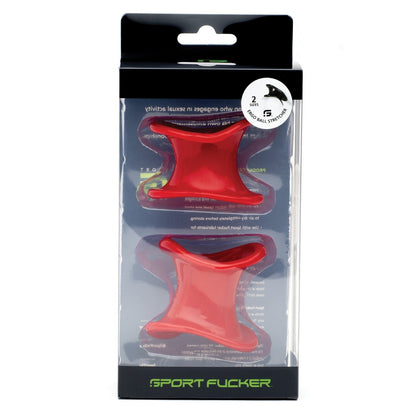 The Sport Fucker Ergonomic Ball Stretcher Kit features two red silicone, hollow cylindrical ball stretchers with wide rims in different sizes. Presented vertically in the clear plastic section of the packaging, it showcases the Sport Fucker branding.