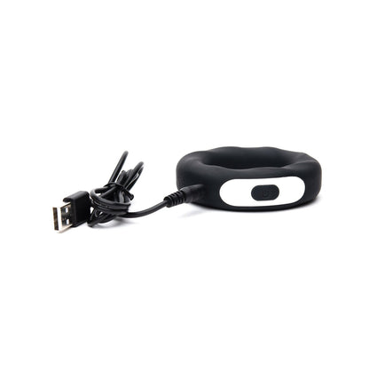 The Sport Fucker Motovibe Rev Cockring by Sport Fucker is a stylish black circular device made of medical-grade silicone, featuring a white oval button with a power symbol. It comes with a USB rechargeable cable, combining functionality and modern elegance in one package.