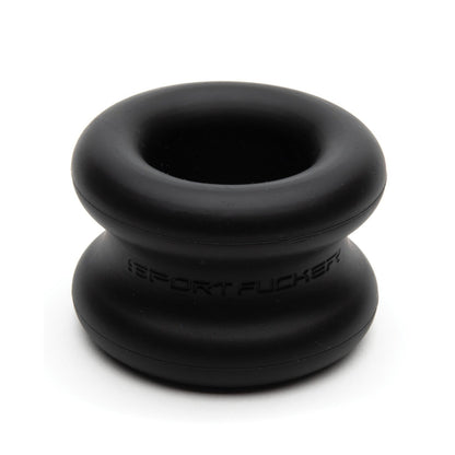 The Sport Fucker Muscle Ball Stretcher by Sport Fucker is a black silicone ring with a stretchy, smooth double-layered design. It has embossed text around its middle section, rounded shape, and matte finish, combining style and comfort.