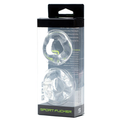 The Sport Fucker Revolution Combo Set comes in a clear plastic box featuring two vertically stacked transparent silicone rings. The packaging displays black and green branding with Sport Fucker labels, emphasizing its dual role as a cockring and ball stretcher.