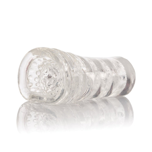 A clear, textured plastic sleeve from California Exotic Novelties, similar to a silicone masturbation sleeve, lies on its side with a slightly reflective surface. This cylindrical design features internal grooves and dots for optimal grip or holding items like the Sue Johanson Head Honcho.